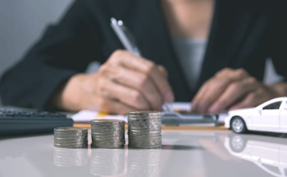 Car insurance and car service. Businesswoman with stack of coins and toy car, business and financial concept.