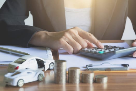 Car insurance and car service. Businesswoman with stack of coins and toy car, business and financial concept.