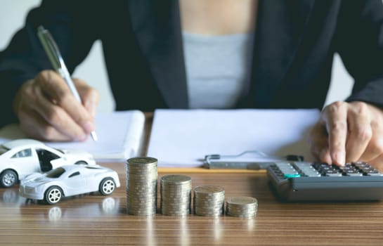 Car insurance and car service. Businesswoman with stack of coins and toy car, business and financial concept.