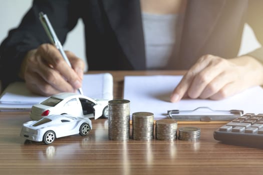 Car insurance and car service. Businesswoman with stack of coins and toy car, business and financial concept.