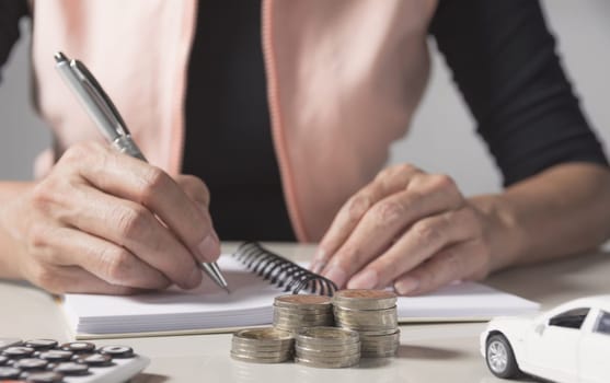 Car insurance and car service. Businesswoman with stack of coins and toy car, business and financial concept.