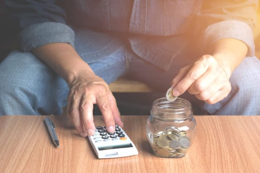 Saving money concept and hand putting money coin in the glass jar for financial and accounting concept.