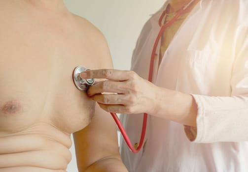 Female doctor using stethoscope for check and listen to heart and lungs of patient at a hospital.