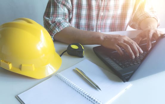 Architect engineer working concept with laptop and construction tools or safety equipment on table.