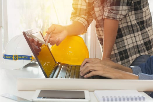 Architect engineer using laptop for working with yellow helmet and laptop on table.