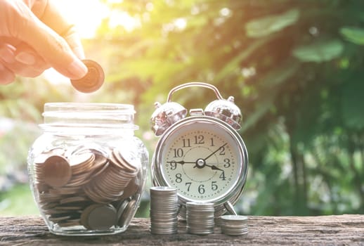 Hand drop a coin in glass jar with money coin stack growing for business. financial and accounting concept.