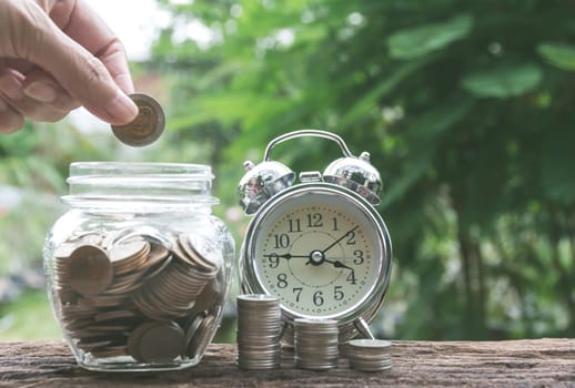 Hand drop a coin in glass jar with money coin stack growing for business. financial and accounting concept.