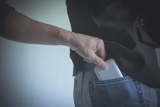 Close-up of a the hand of thief stealing the wallet to a woman. Thief stealing wallet from back pocket of a woman.