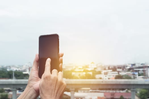 Woman hand holding and using smart phone with buildings background.