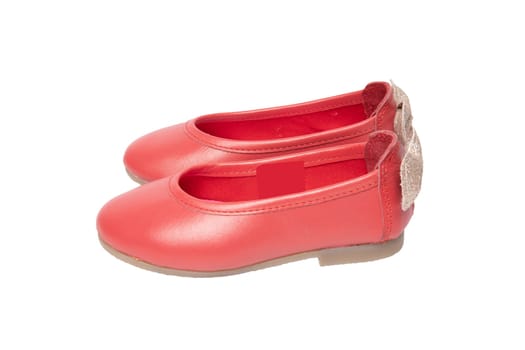 Red shoes. Closeup of red girls shoes with a golden bow isolated on a white background. Fashionable footwear.