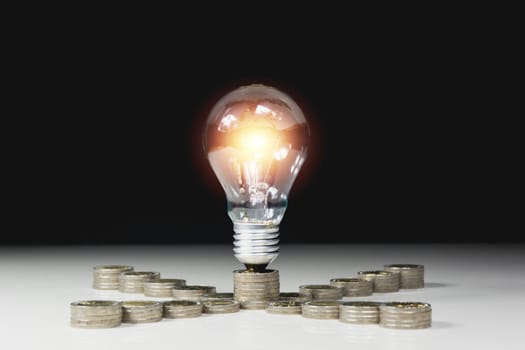 Energy saving light bulb with stacks of coins and calculator for financial, accounting and saving concept.