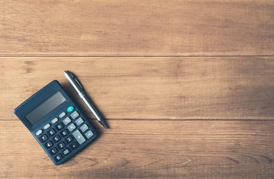 A calculator and pen on wooden background with copy space for insert text.