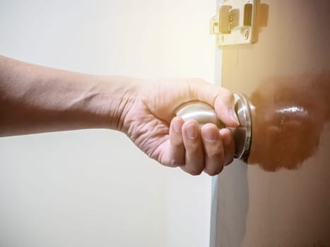 Close up of hand holding a door knob, opening or closing the door.