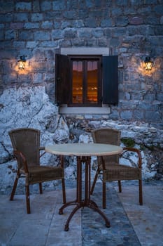 Empty table and wicker chairs outside a local cafe in Petrovac in the evening, Montenegro