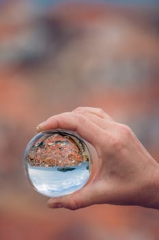Historical Dubrovnik Old Town on the Adriatic coast in Montenegro reflected in a transparent round sphere ball held by a caucasian man