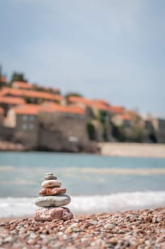 Pile of stacked stones on the beach in front of the historical Sveti Stefan old town, coast of Montenegro