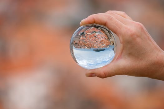 Historical Dubrovnik Old Town on the Adriatic coast in Montenegro reflected in a transparent round sphere ball held by a caucasian man