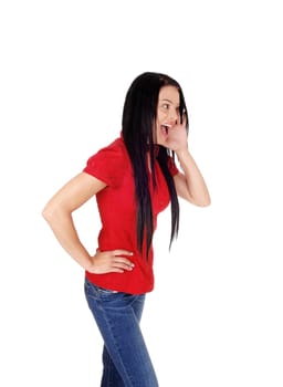 A slim young woman standing profile in jeans and red blouse with one.hand on her mouth and screaming, isolated for white background.