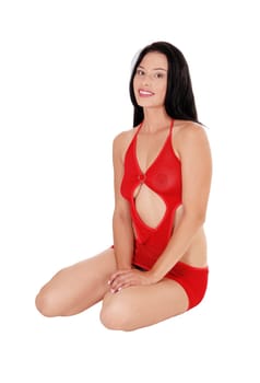 A lovely young lady in  red lingerie and high heels sitting on the floor.looking into the camera smiling, isolated for white background.
