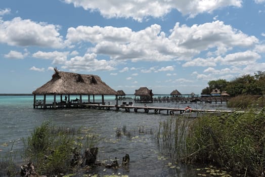 houses and pier on the shore of the lagoon of bacalar, quintana roo, mexico.