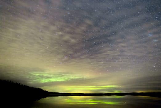 Northern Lights over Lake with clouds and stars.
