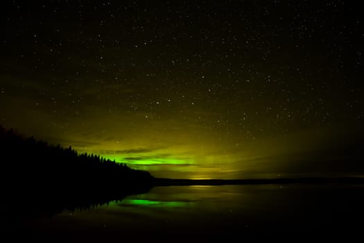 Northern Lights over Lake with clouds and stars.
