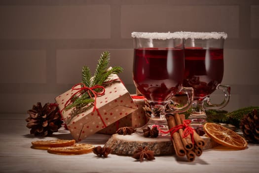 Still life with glasses of mulled wine or fruit tea, gift boxes and christmas decorations on a wooden table. New year and Christmas.