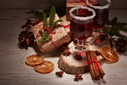 Still life with glasses of mulled wine or fruit tea, gift boxes and christmas decorations on a wooden table. New year and Christmas.