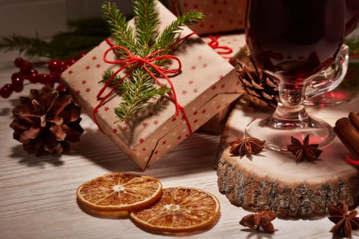 Still life with glasses of mulled wine or fruit tea, gift boxes and christmas decorations on a wooden table. New year and Christmas.