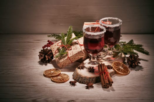 Still life with glasses of mulled wine or fruit tea, gift boxes and christmas decorations on a wooden table. New year and Christmas.