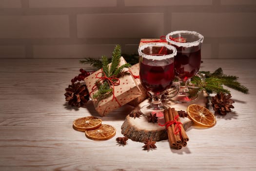 Still life with glasses of mulled wine or fruit tea, gift boxes and christmas decorations on a wooden table. New year and Christmas.