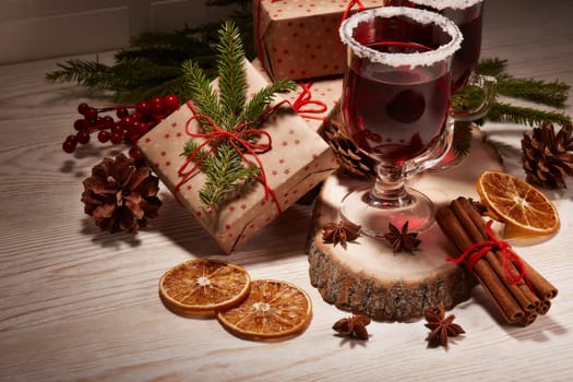 Still life with glasses of mulled wine or fruit tea, gift boxes and christmas decorations on a wooden table. New year and Christmas.