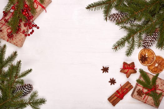 Fir branches, cones and gift boxes on a white wooden background. Top view with copy space. New Year and Christmas