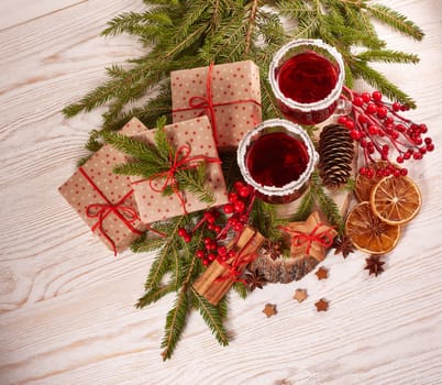 Still life with glasses of mulled wine or fruit tea, gift boxes, gingerbread cookies and christmas decorations on a wooden table.Top view. Christmas and New Year treat.