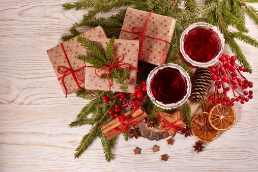 Still life with glasses of mulled wine or fruit tea, gift boxes, gingerbread cookies and christmas decorations on a wooden table.Top view. Christmas and New Year treat.