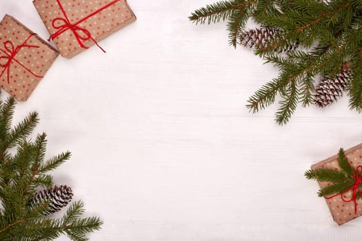 Fir branches, cones and gift boxes on a white wooden background. Top view with copy space. New Year and Christmas