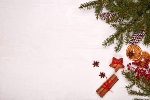 Fir branches, cones and gingerbread cookies on a white wooden background. Top view with copy space. New Year and Christmas