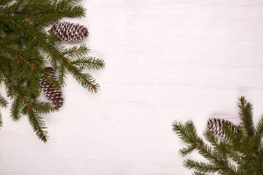 White wooden background with fir branches and cones. New Year and Christmas