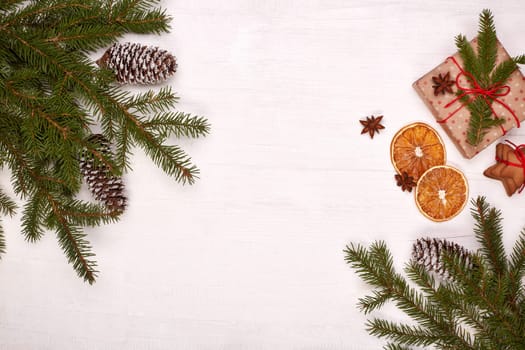 Fir branches, cones and gift boxes on a white wooden background. Top view with copy space. New Year and Christmas