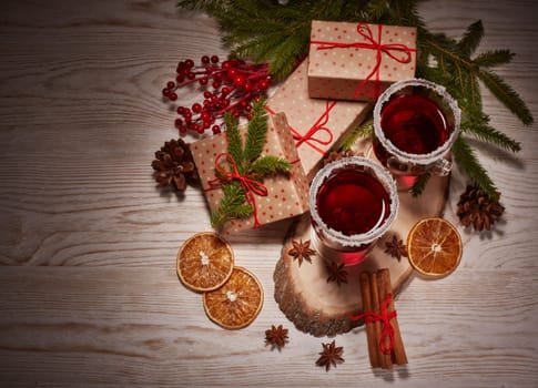 Still life with glasses of mulled wine or fruit tea, gift boxes and christmas decorations on a wooden table.Top view. New year and Christmas.