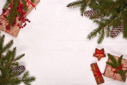 Fir branches, cones and gift boxes on a white wooden background. Top view with copy space. New Year and Christmas