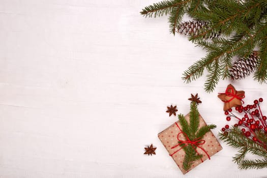 Fir branches, cones and gift boxes on a white wooden background. Top view with copy space. New Year and Christmas