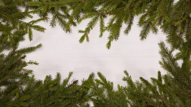 White wooden background with frame from fir branches. New Year and Christmas