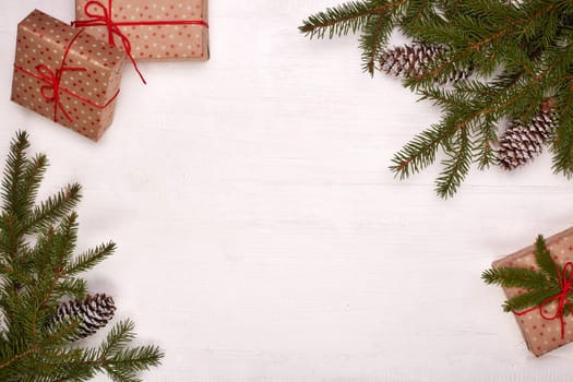 Fir branches, cones and gift boxes on a white wooden background. Top view with copy space. New Year and Christmas