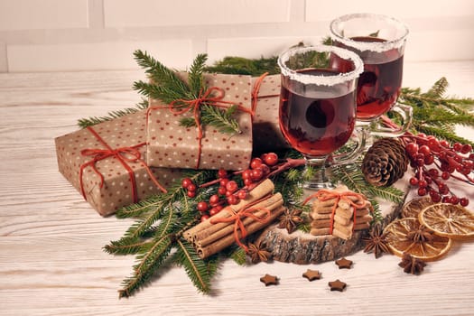 Still life with glasses of mulled wine or fruit tea, gift boxes, gingerbread cookies and christmas decorations on a wooden table. Christmas and New Year treat.