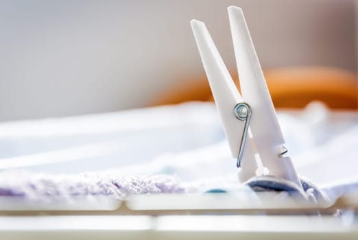 close-up of a white clothespin keeping the clothes hanging on the Clothesline