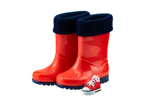 Children shoes and boots. Closeup of a pair red rubber boots and a toy isolated on a white background. Kids shoes fashion.