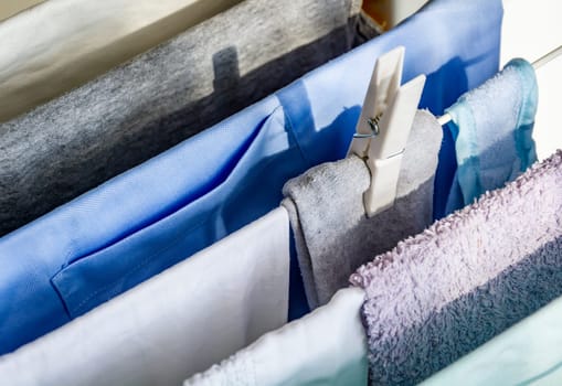 Close up of a white plastic clothespin on a clotheshorse with laundry drying