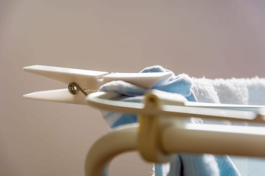 Close up of a white plastic clothespin on a clotheshorse with laundry drying
