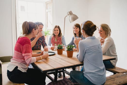 Group of employees at a small coffee shop sitting around a table having a meeting.
